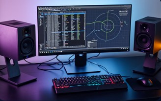 A designer's desk with a widescreen monitor, studio speakers and keyboard